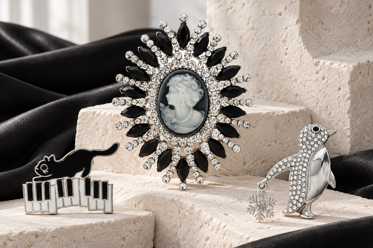 Monochrome cameo, cat on piano keys and silver-tone penguin brooches on ivory stone and black satin
