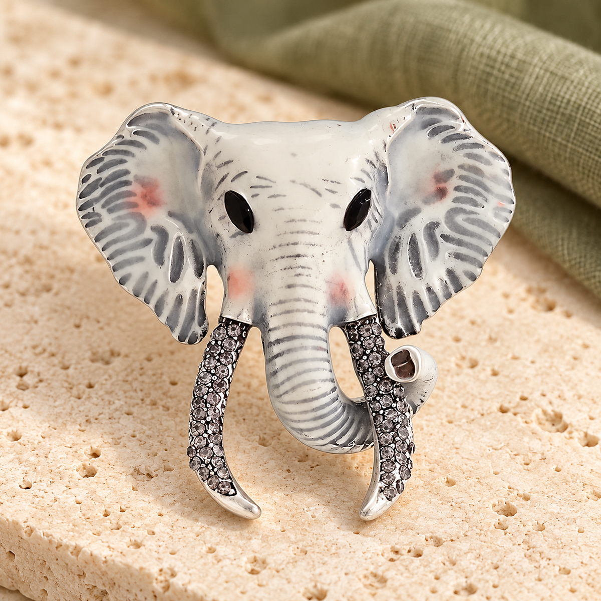 Enamel Elephant Head with Jeweled Tusks Brooch — styled background
