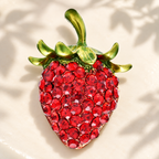 Red Rhinestone Strawberry with Enamel Leaves Brooch — styled background