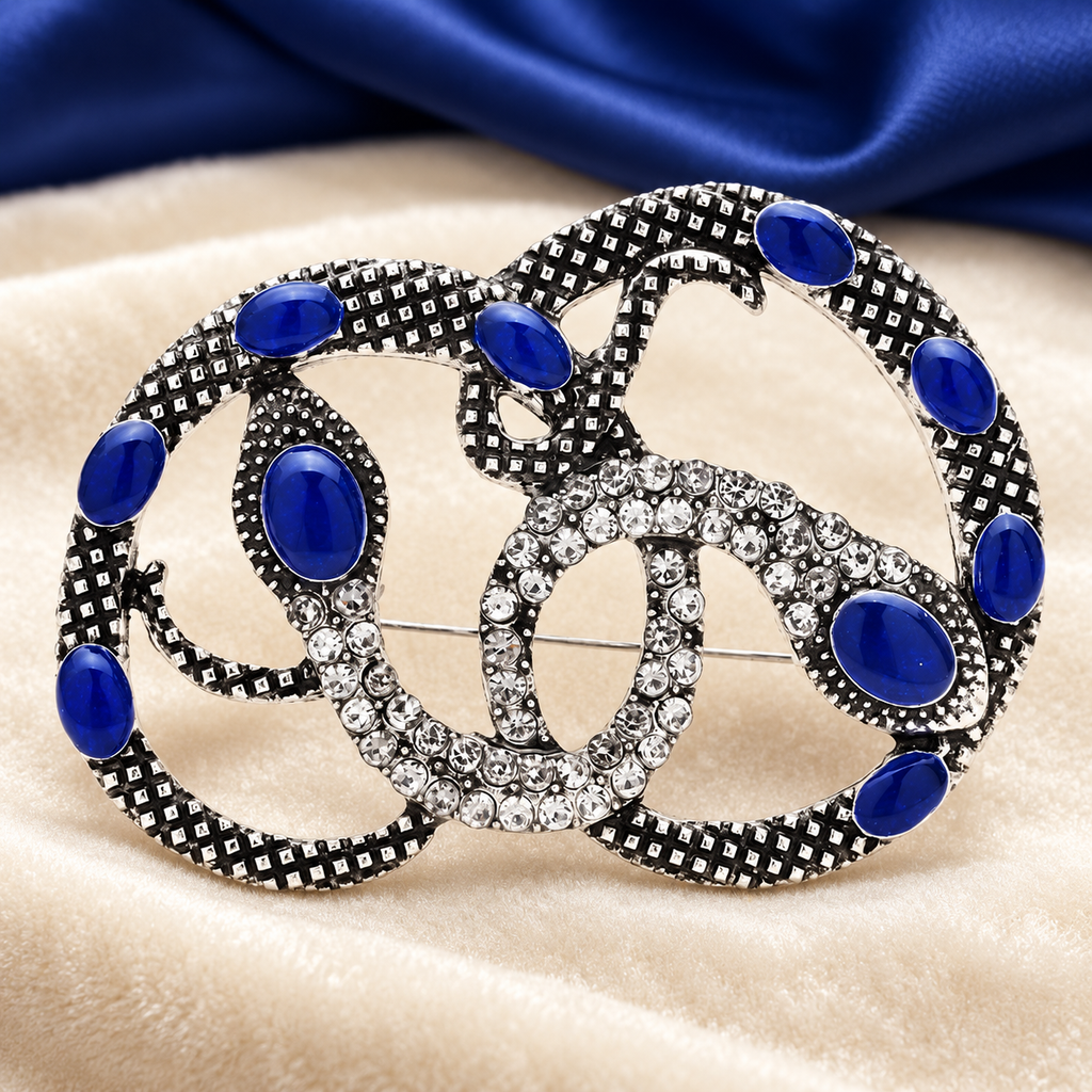 Intertwined Rhinestone Snakes Brooch — styled background
