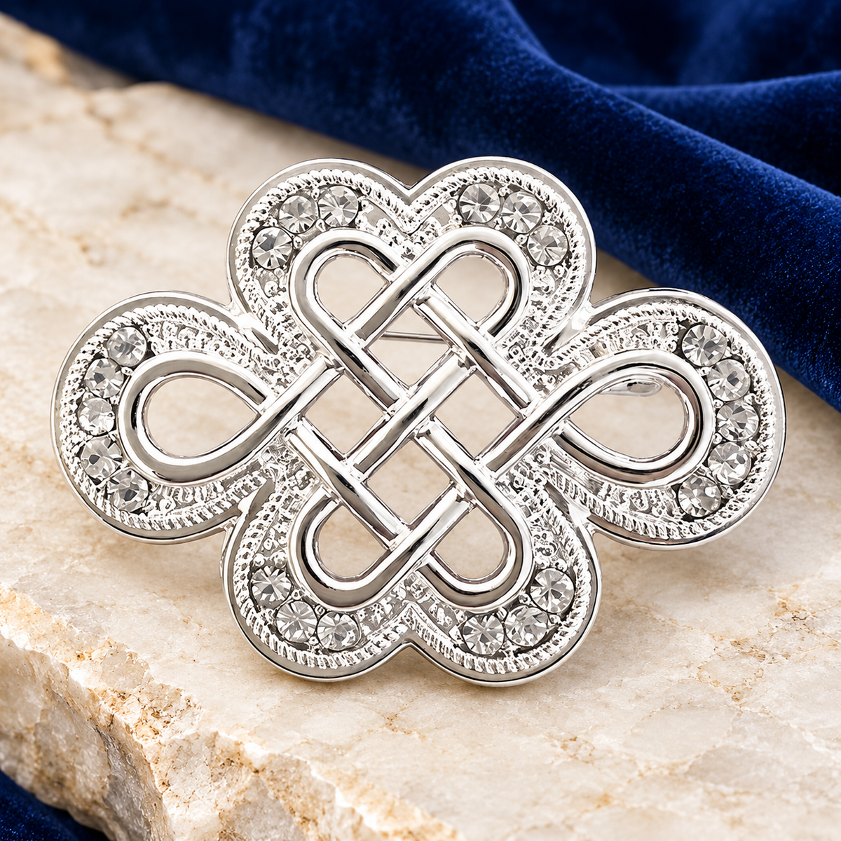 Silver-Tone Jeweled Endless Knot Brooch — styled background