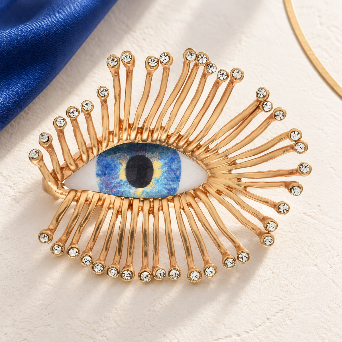 Blue Eye with Radiating Golden Lashes Brooch — styled background