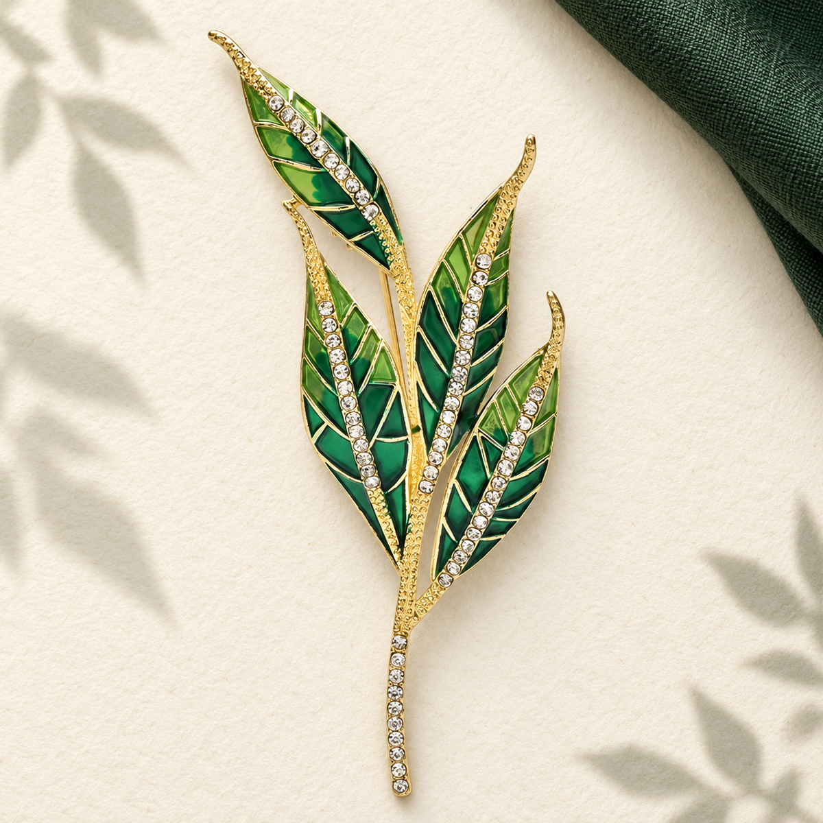 Green Enamel Leaf Sprig with Rhinestone Stem Brooch — styled background