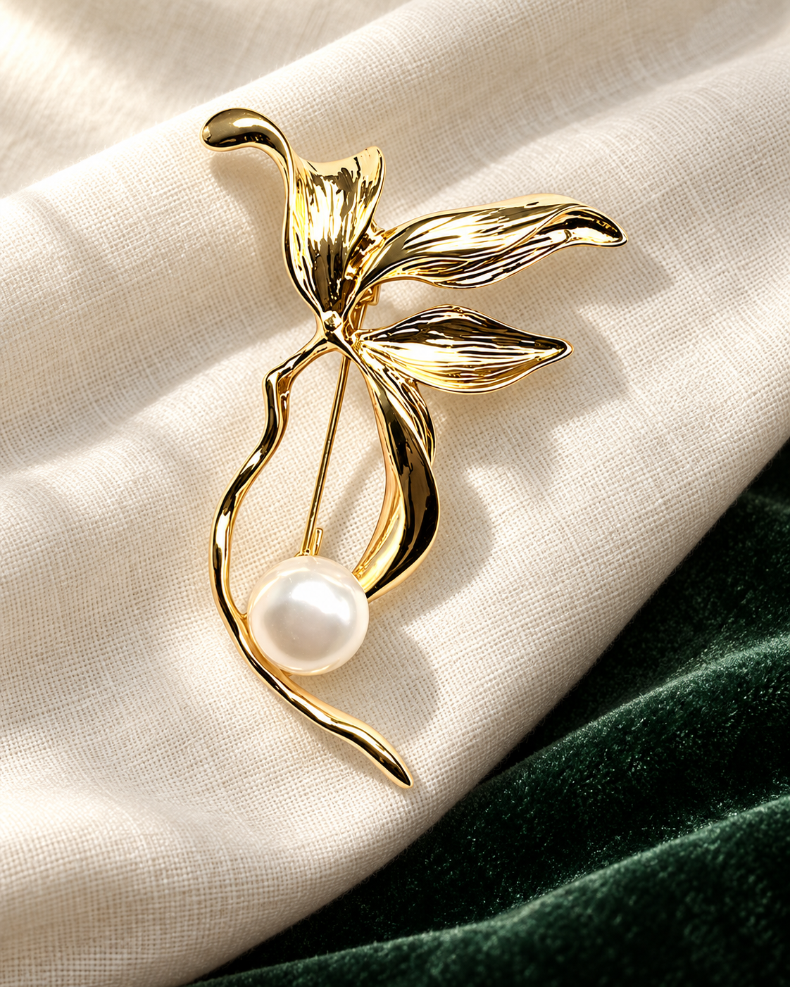 Gold-tone floral brooch with a pearl-look detail on ivory linen and deep green velvet