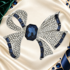 Rhinestone Ribbon Bow with Faceted Center Brooch on an ivory, evergreen and sapphire gallery background