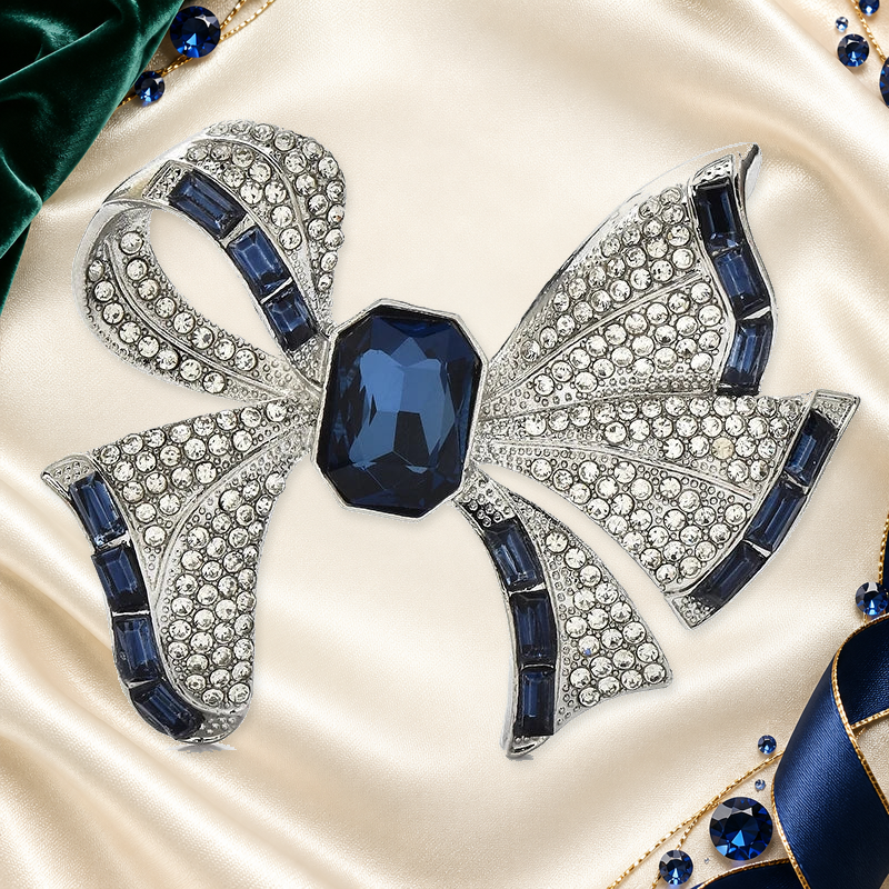 Rhinestone Ribbon Bow with Faceted Center Brooch on an ivory, evergreen and sapphire gallery background