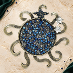 Rhinestone Sun with Curling Rays Brooch on an elegant ivory, evergreen and gold celestial background