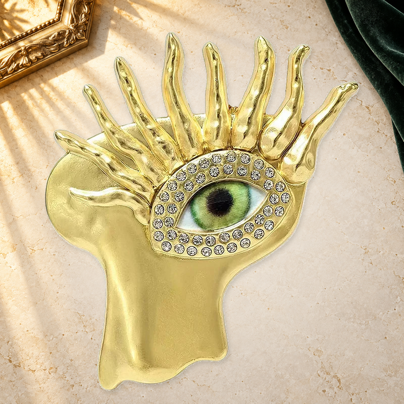 Sculptural Face with Eye Motif Brooch on a complementary display background